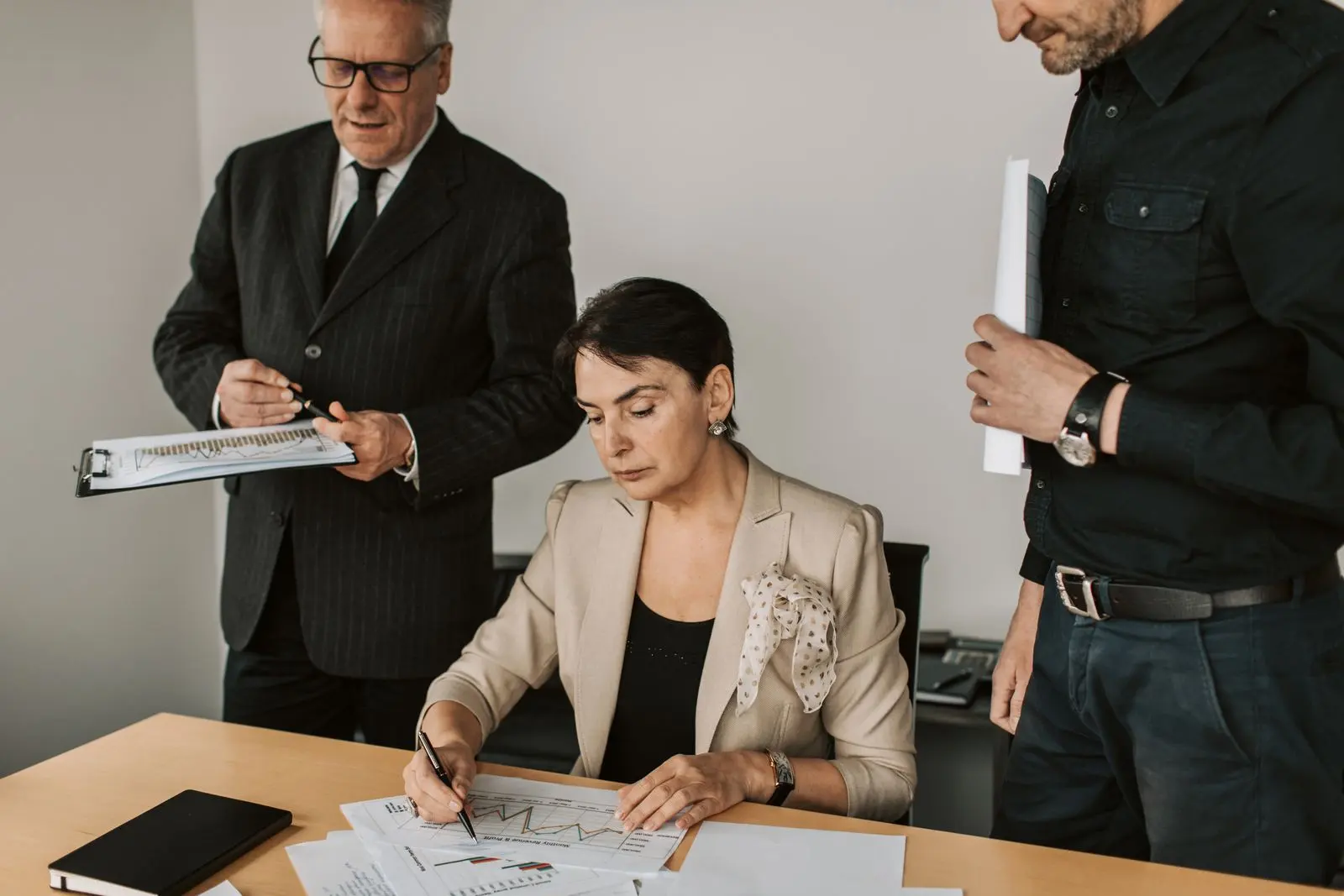 Profissionais em reunião de trabalho revisando documentos de gestão sobre a mesa